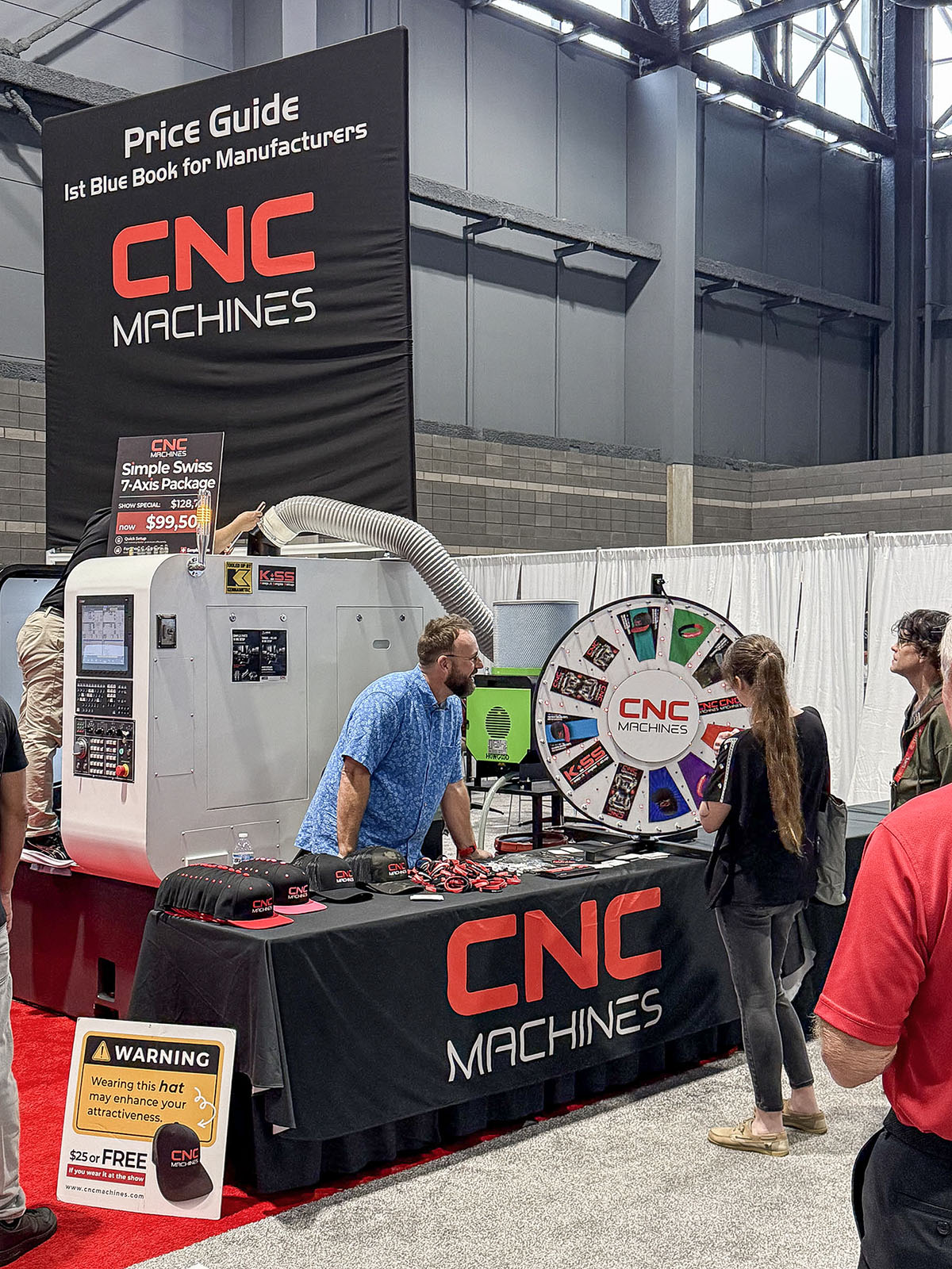 Conversa no pavilhão ao lado de um torno ARIX e de um display do guia de preços da CNC Machines na IMTS 2026