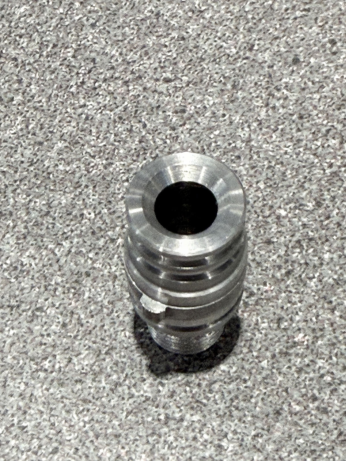 Peça metálica cilíndrica polida, usinada com precisão, exposta na IMTS 2026